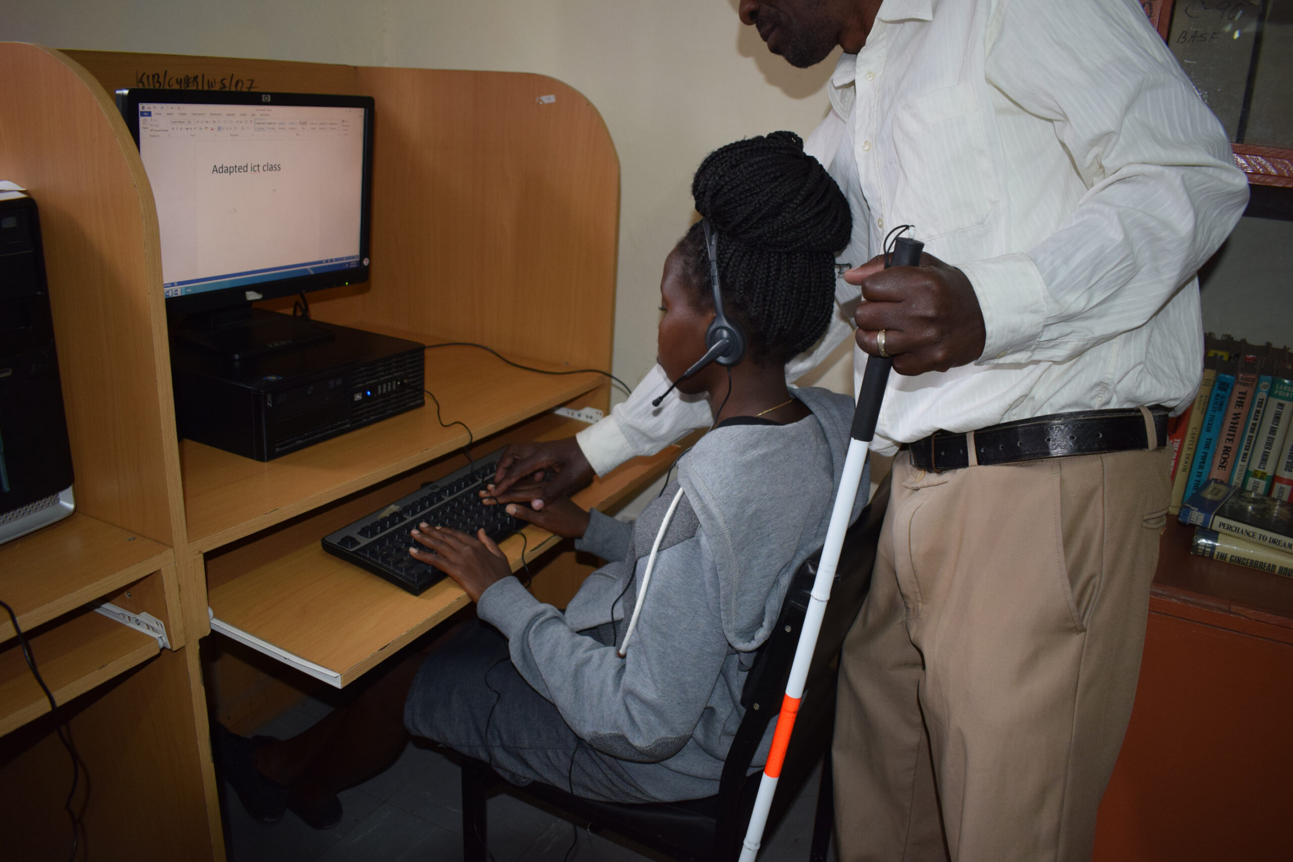 Photo of a blind lady being taught how to use a computer